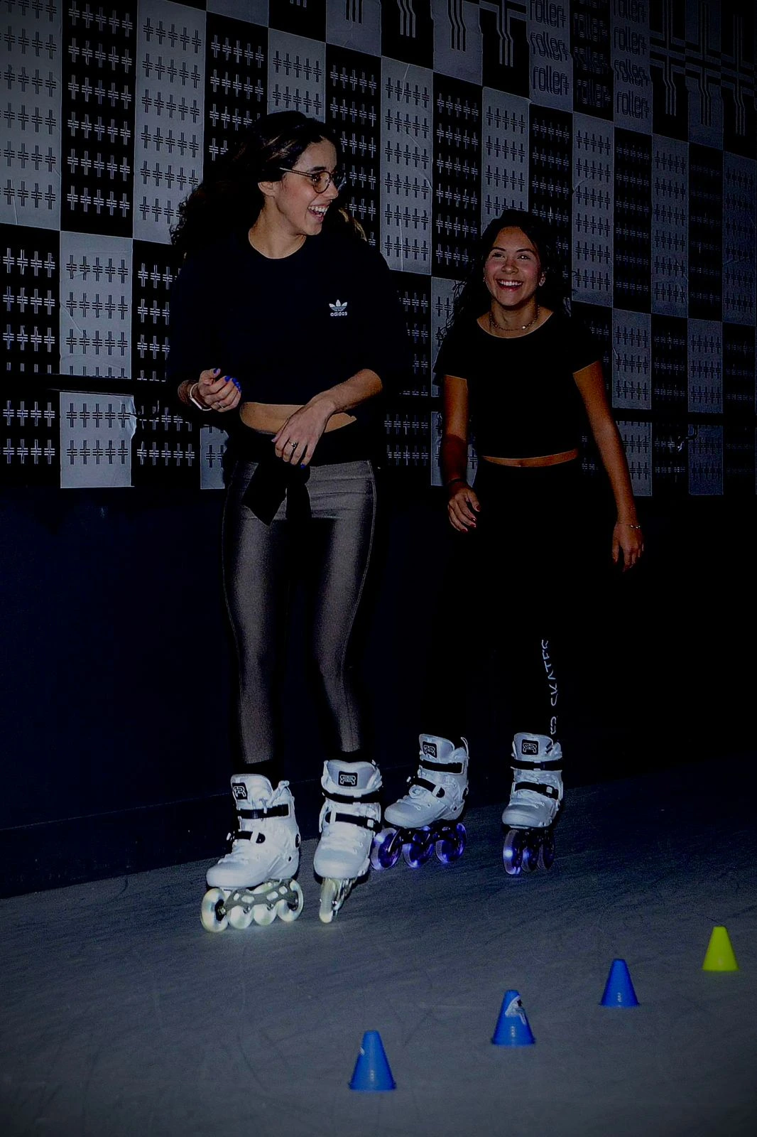 Alunas patinando e sorrindo na pista Roller Plus
